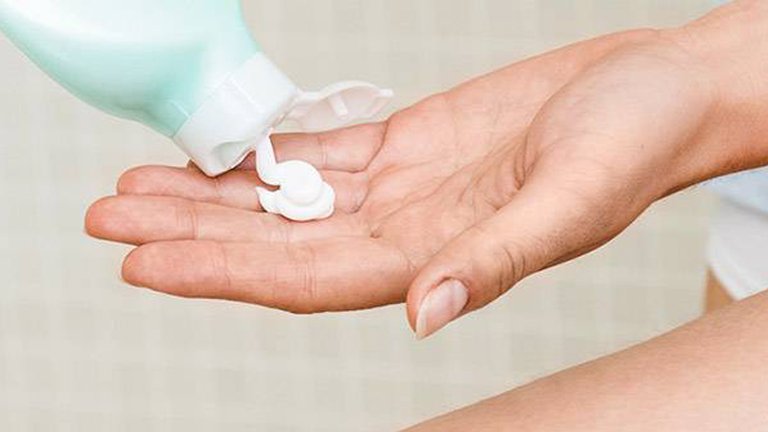 Körpermilch wird aus einer Tube auf eine Hand gedrückt, Körpermilch wird aus einer Tube auf eine Hand gedrückt