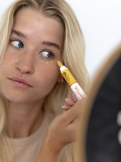 Une femme applique de la crème pour les yeux sur le contour de ses yeux.
